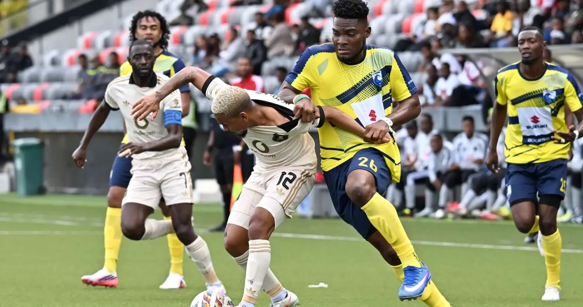 Orlando Pirates player tackling La Cure Waves opponent