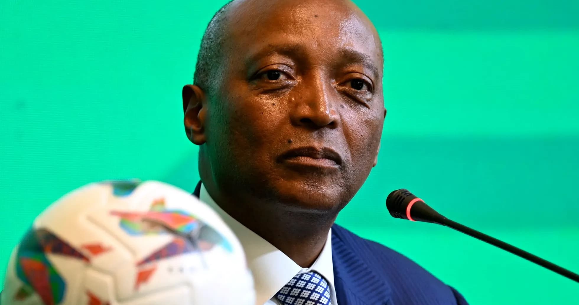 Official speaking at press conference with football