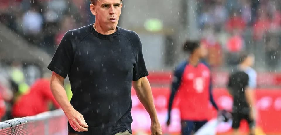 Coach walking on the sideline during rainy match