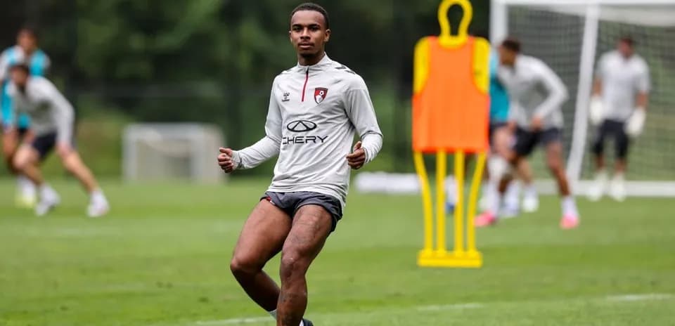 Player training on the pitch with teammates in background