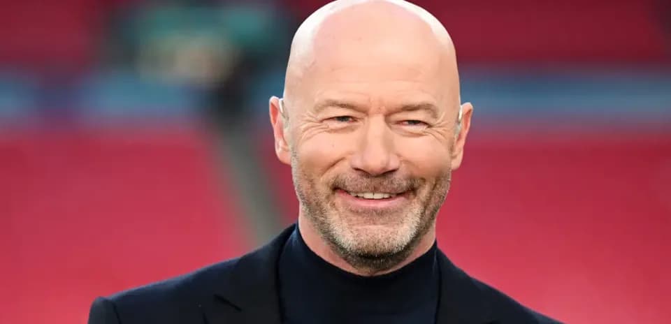 Man smiling in a black suit at stadium
