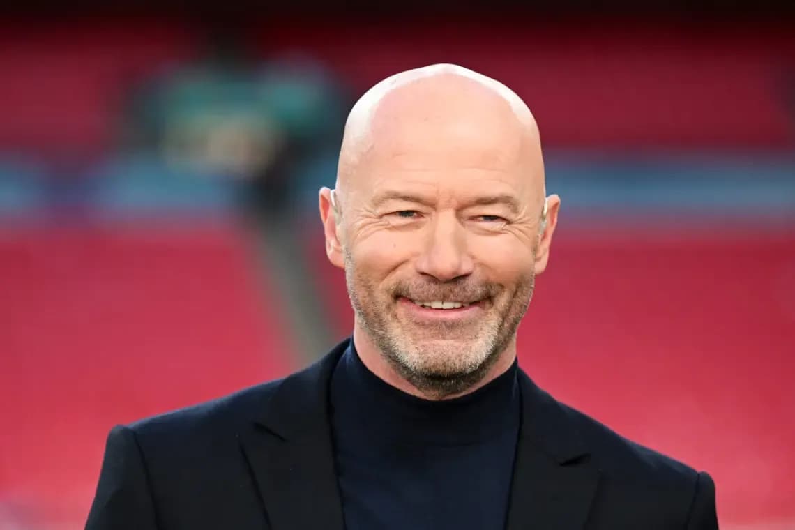 Man smiling in a black suit at stadium