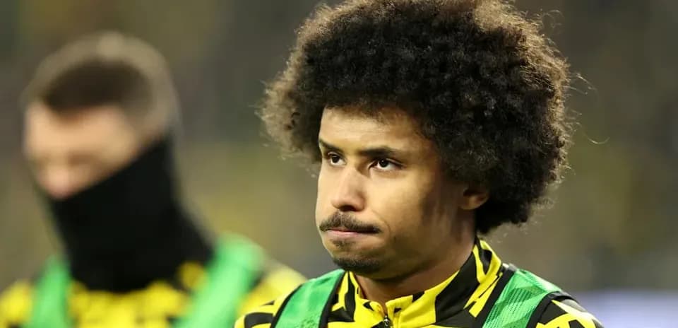 Player in yellow and black kit on sidelines