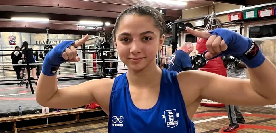 Female boxer posing in training gym with gloves