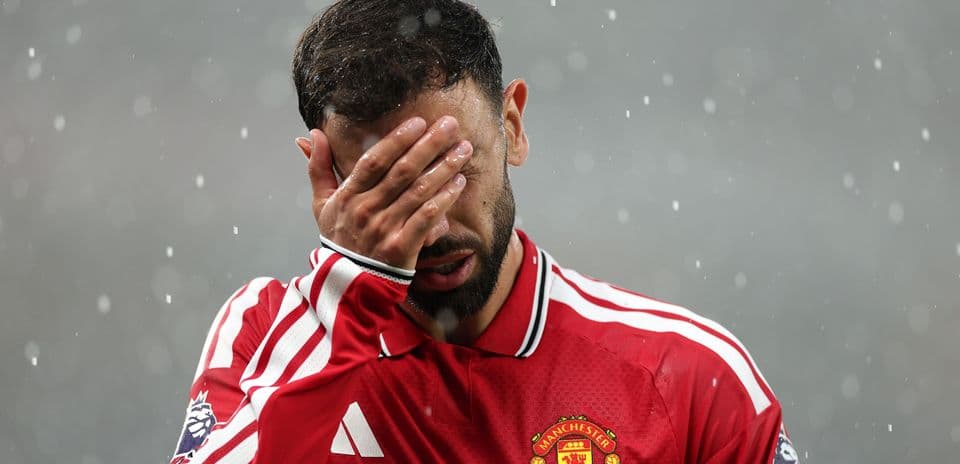 Player in red jersey covering face in rain
