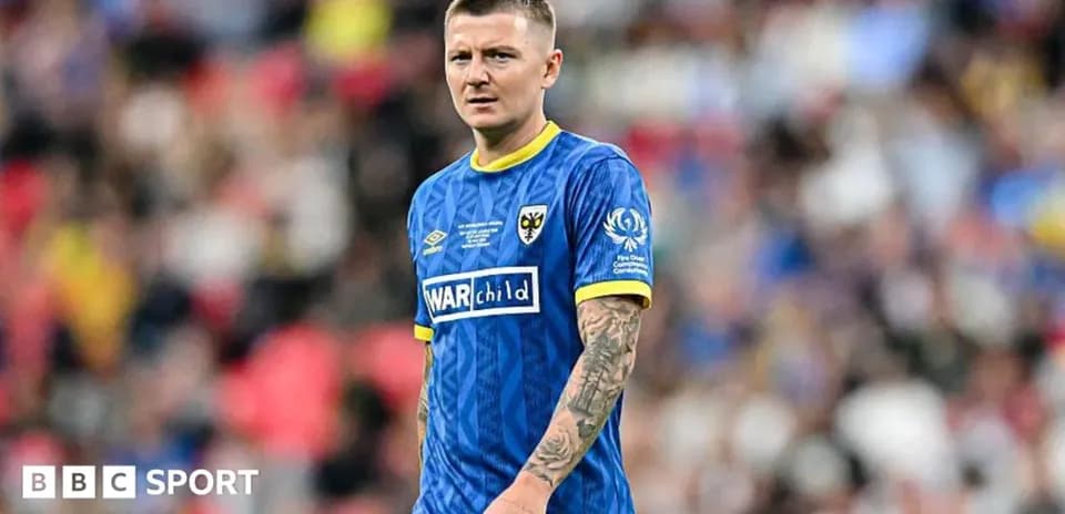 Player in blue kit on football field during match