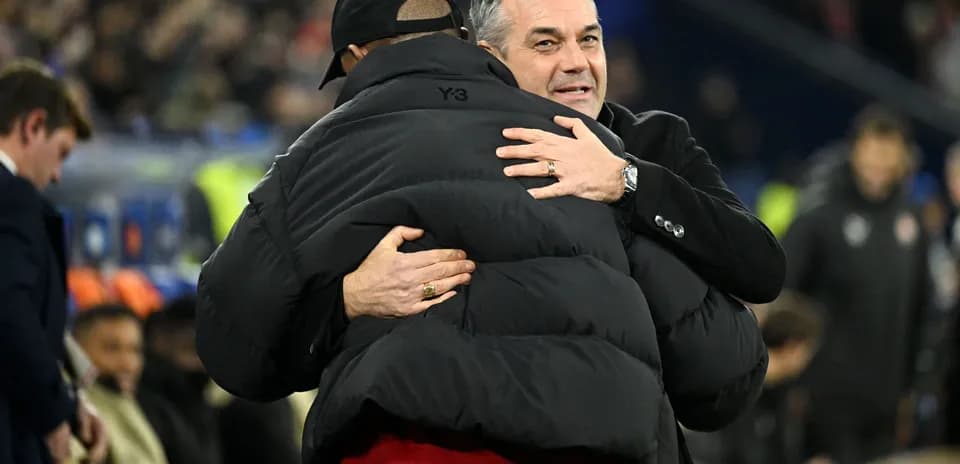 Two coaches embracing on the sidelines