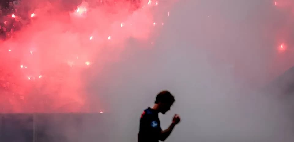 Player celebrating in front of smoke and flares
