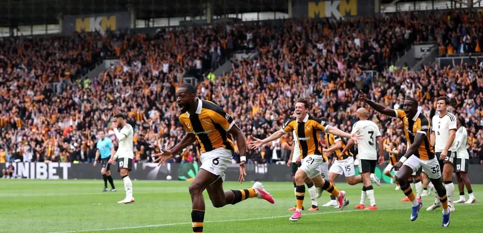 Players celebrating a goal with fans in the background
