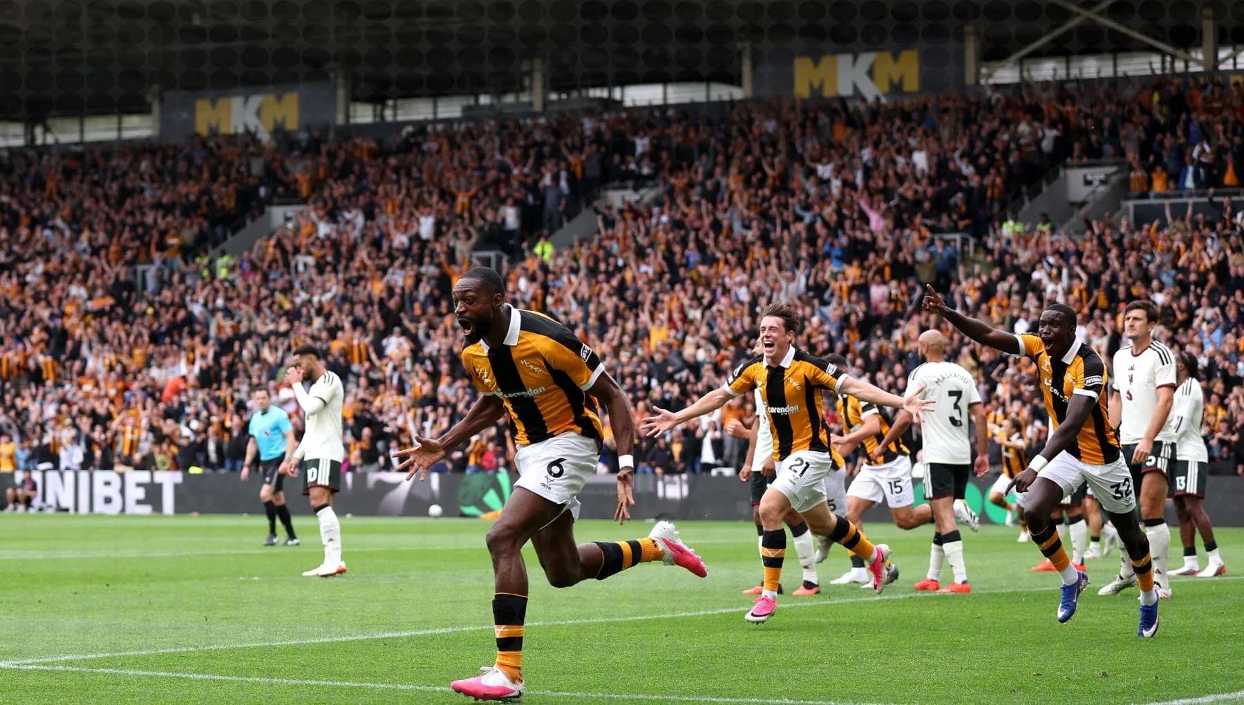 Players celebrating a goal with fans in the background
