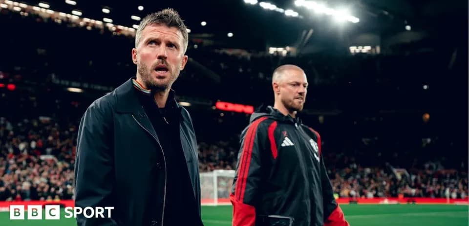 Coaches walking on the pitch at Old Trafford
