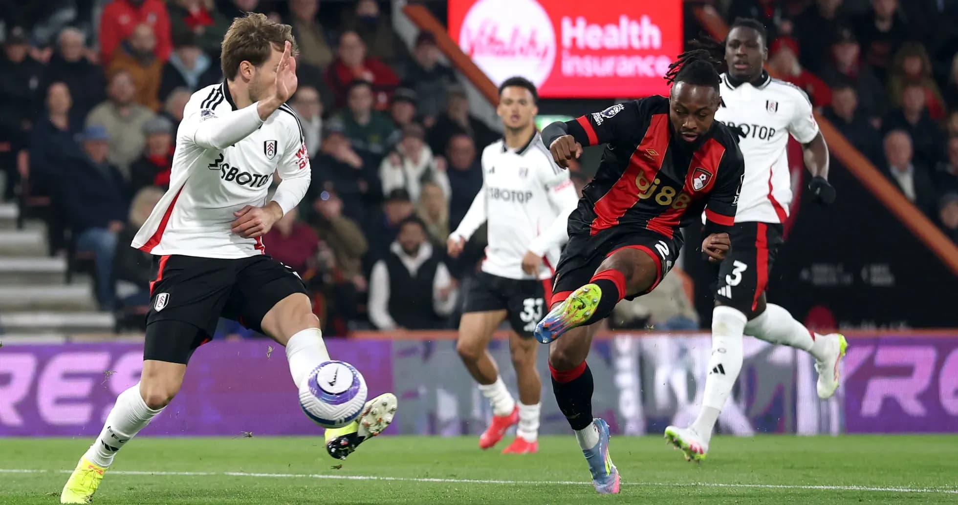 Fulham player challenging Bournemouth opponent for the ball
