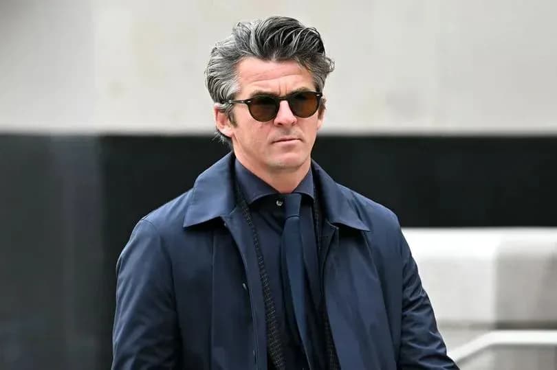 Man in sunglasses walking outdoors in a coat