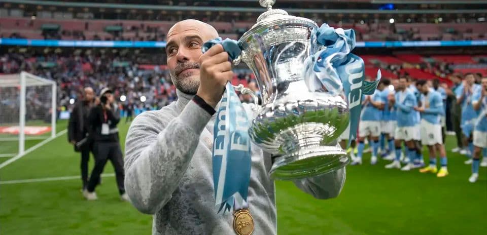 Manager holding trophy on pitch after victory