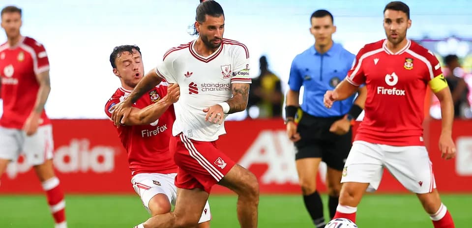 Player in white jersey dribbling past opponent in red