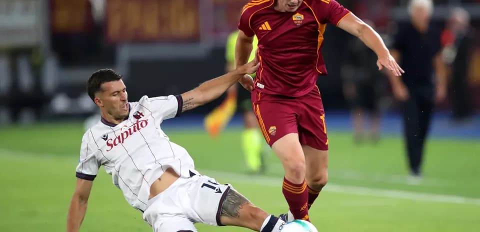 Bologna player tackling AS Roma opponent during match