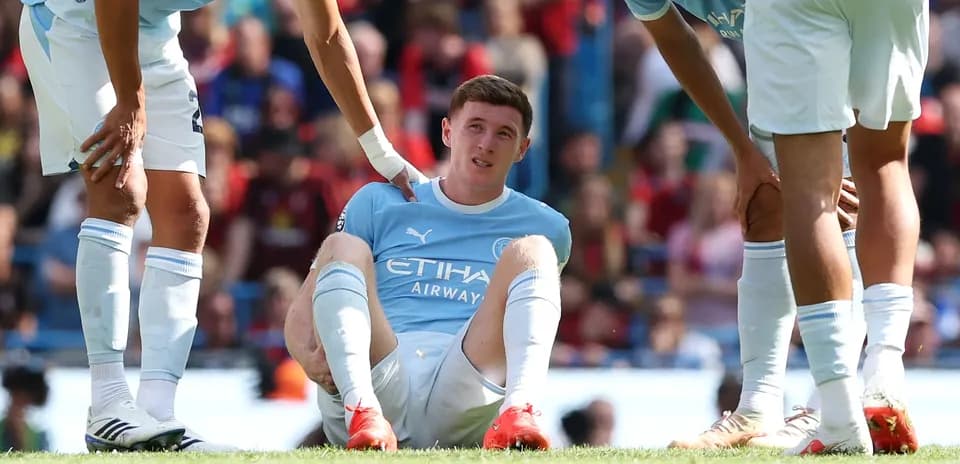 Player sitting on field with teammates assisting