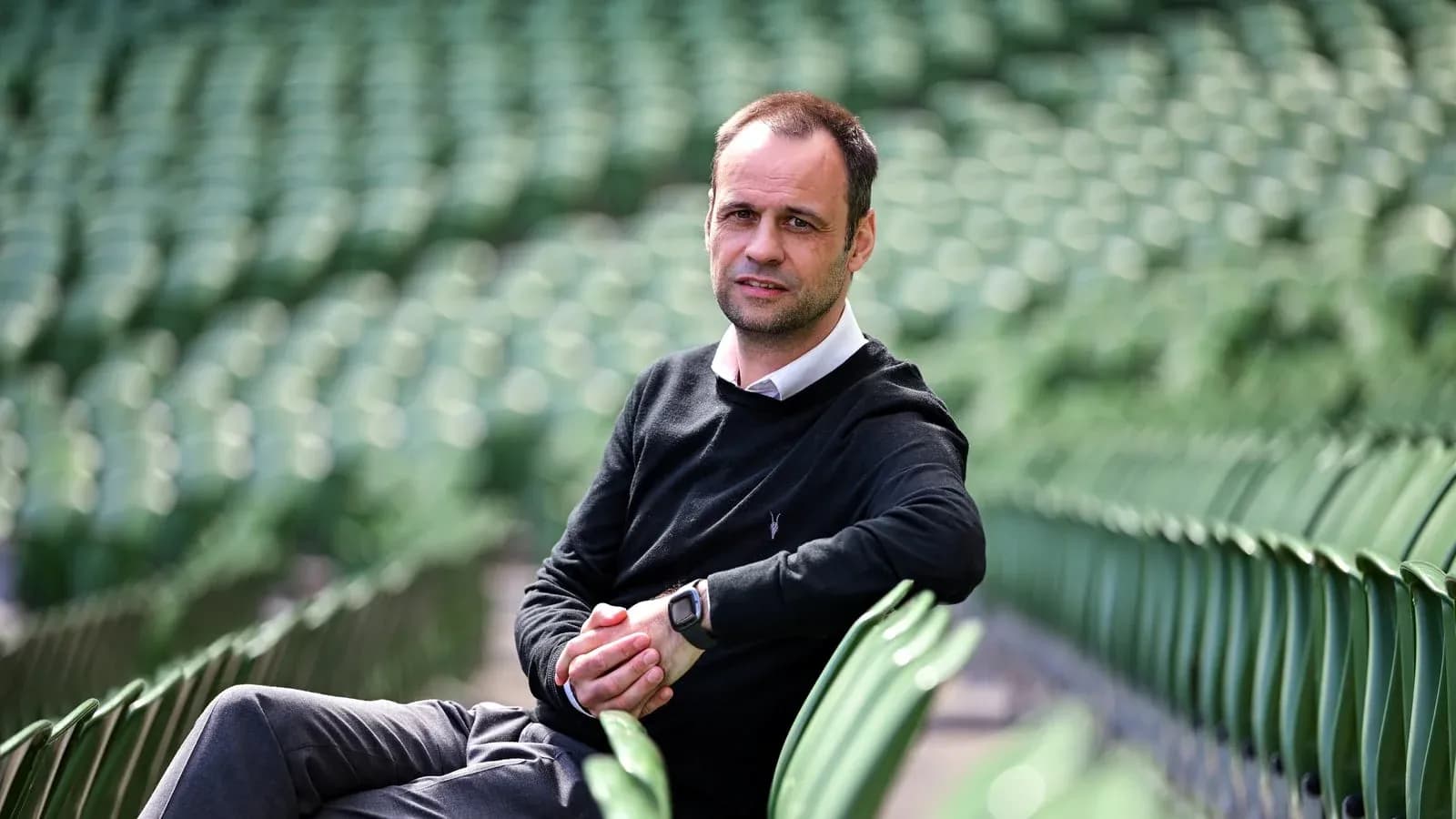 Man sitting on stadium seats, looking at camera