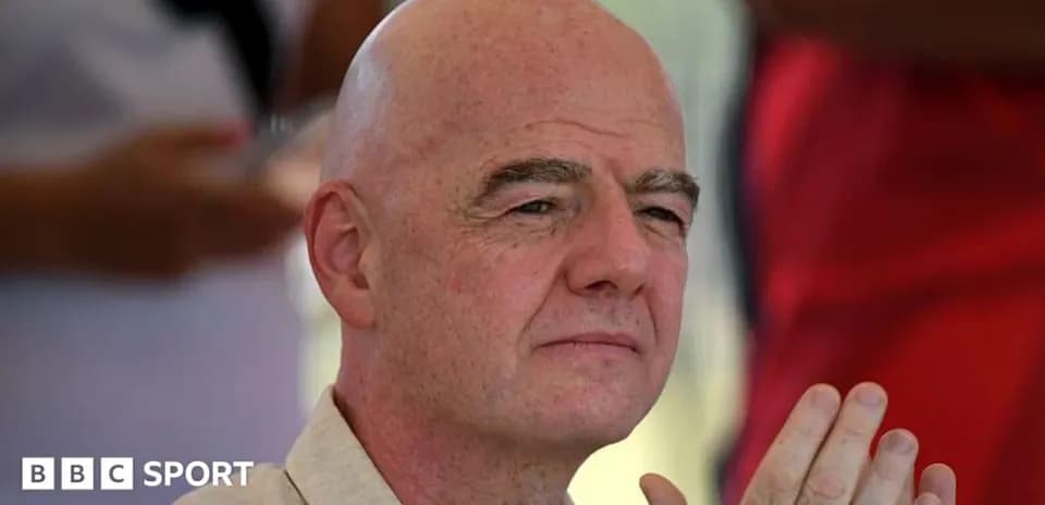 Man with bald head sitting outdoors, hands clasped