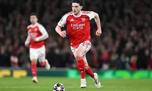 Arsenal player sprinting towards the ball on field