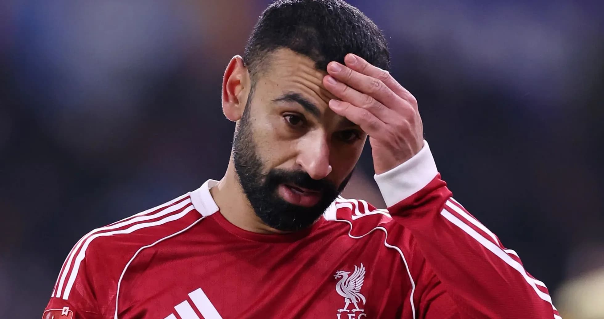 Player in red jersey during match, hand on forehead