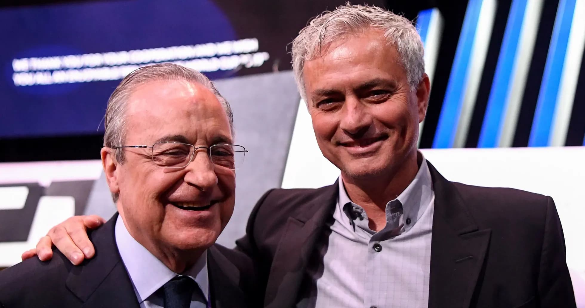 Two men smiling at event, one in suit