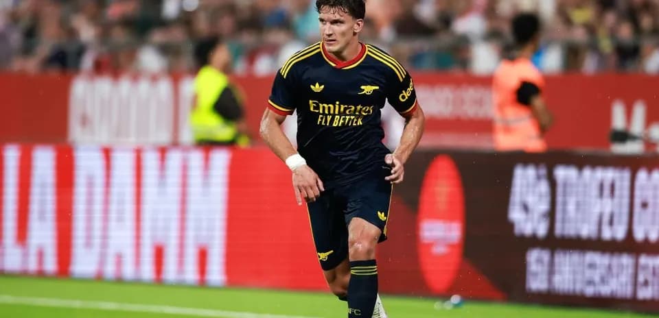 Player in Arsenal kit dribbling the ball on field