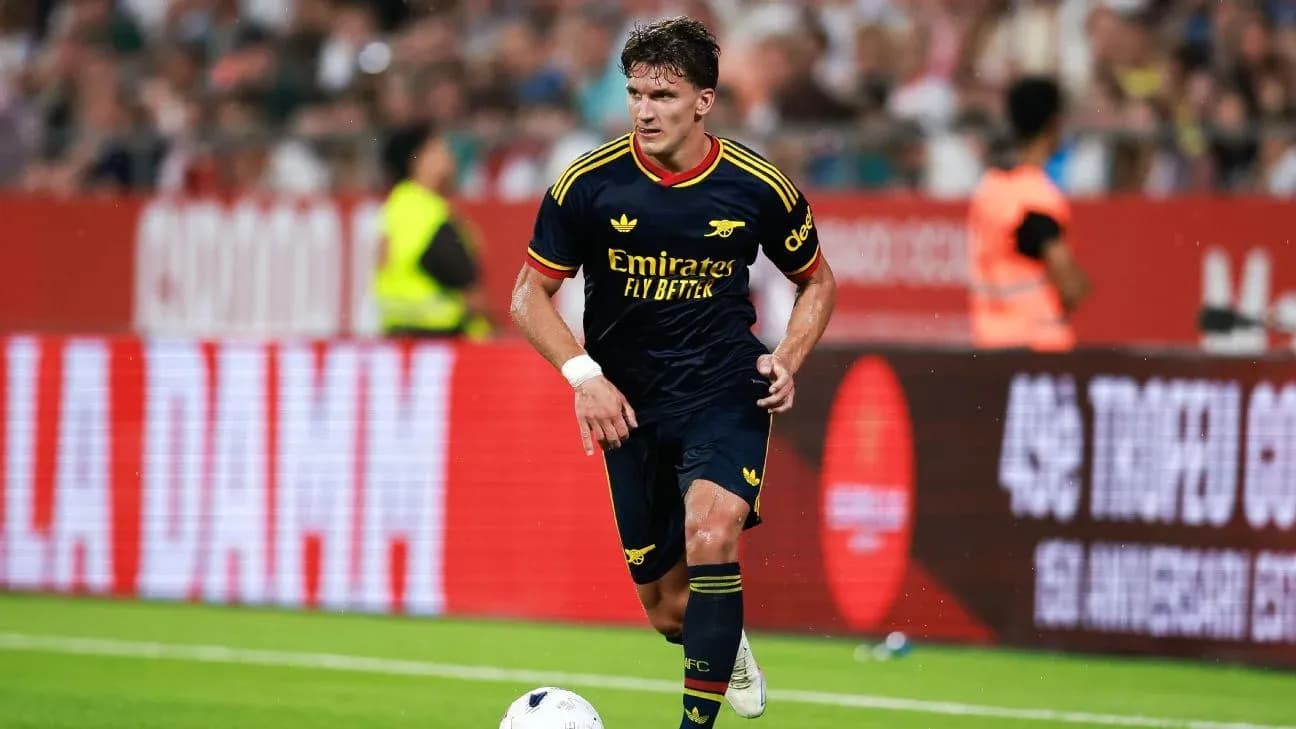 Player in Arsenal kit dribbling the ball on field