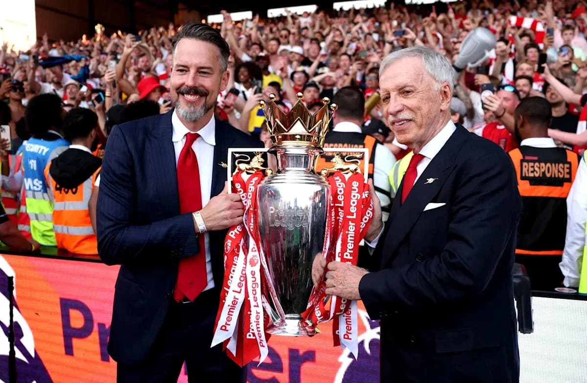 Two officials holding Premier League trophy with fans cheering