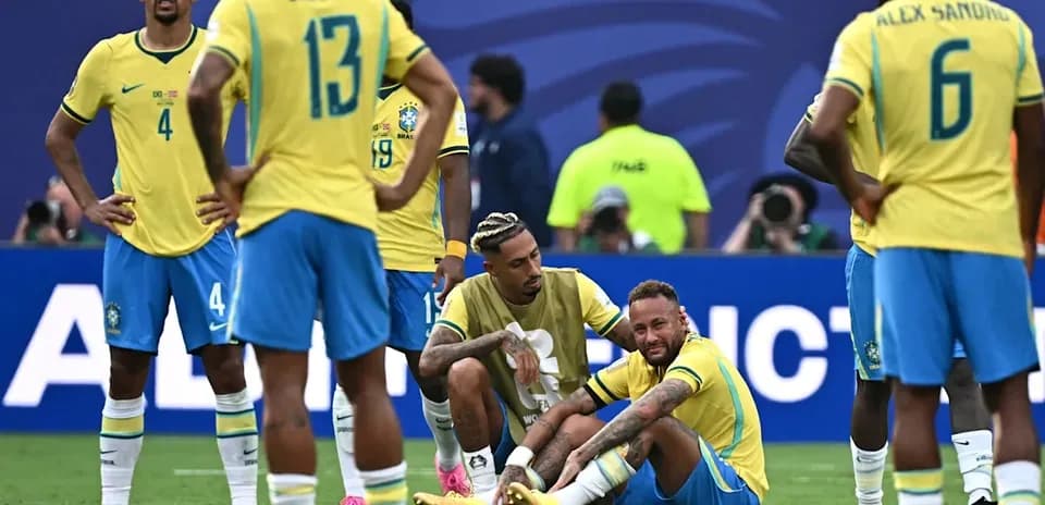 Neymar sitting on field with teammates surrounding