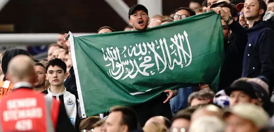 Fan holding Saudi Arabia flag in the stands