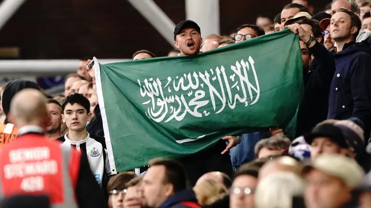 Fan holding Saudi Arabia flag in the stands