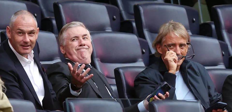 Three men seated in stadium, watching the match