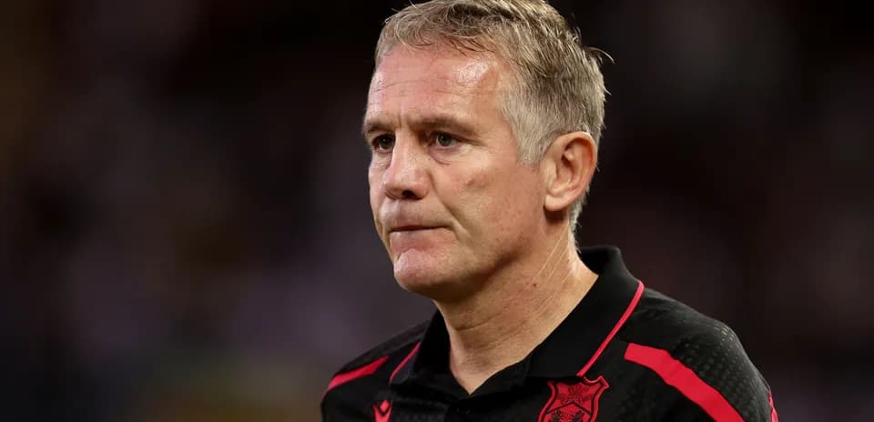 Coach in black shirt with red accents during match