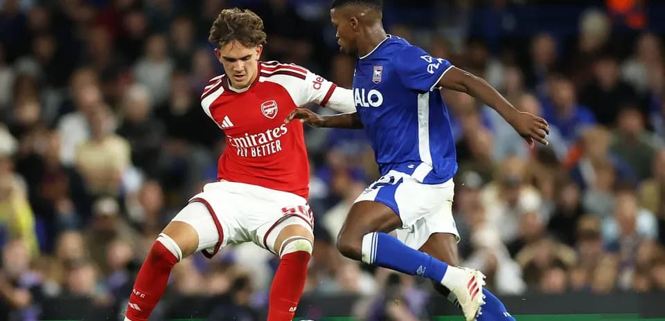 Player in red challenges player in blue for the ball