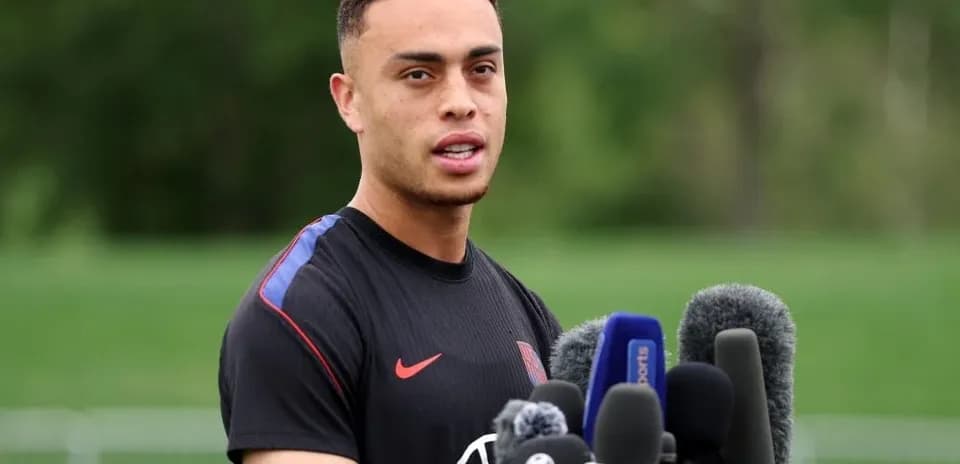 Player speaking at press conference with microphones