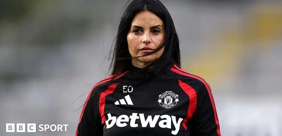 Coach in Manchester United training attire on pitch