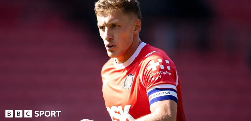 Player in red jersey with captain's armband on field