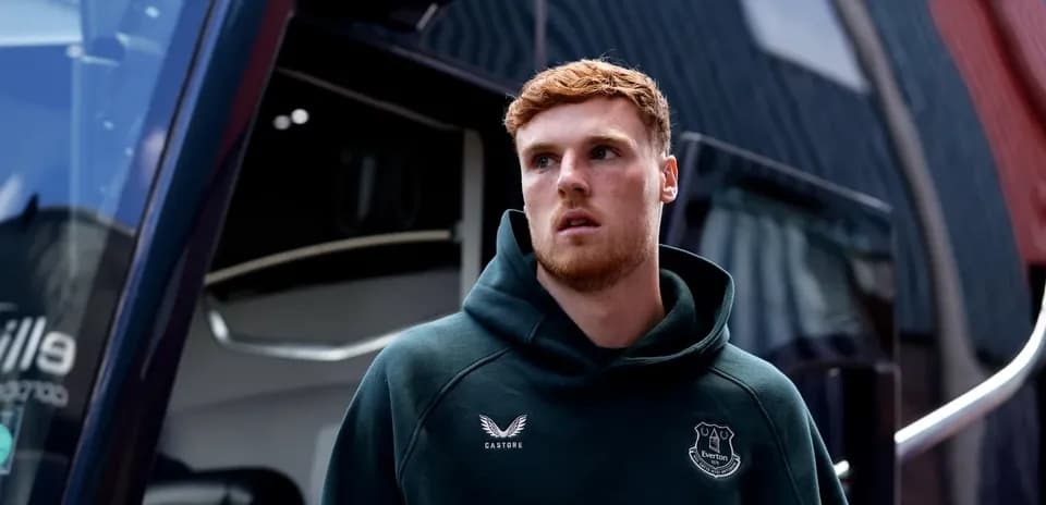 Player wearing Everton hoodie near team bus