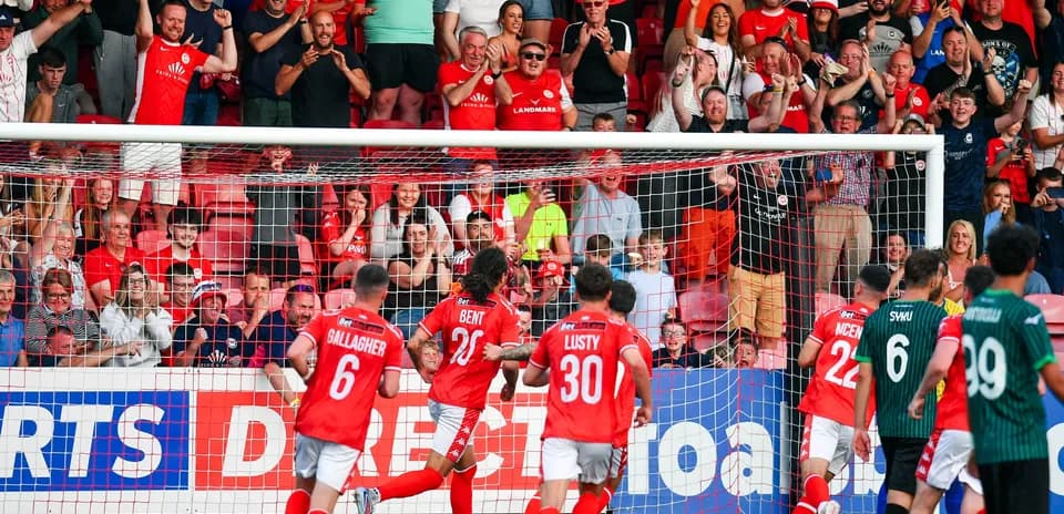 Larne players celebrating a goal with fans
