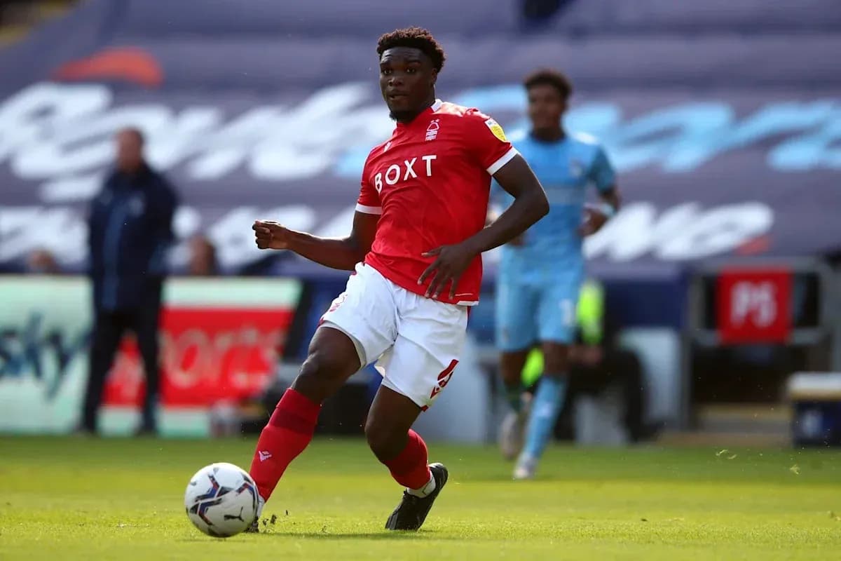 Player in red kit dribbling the ball on field