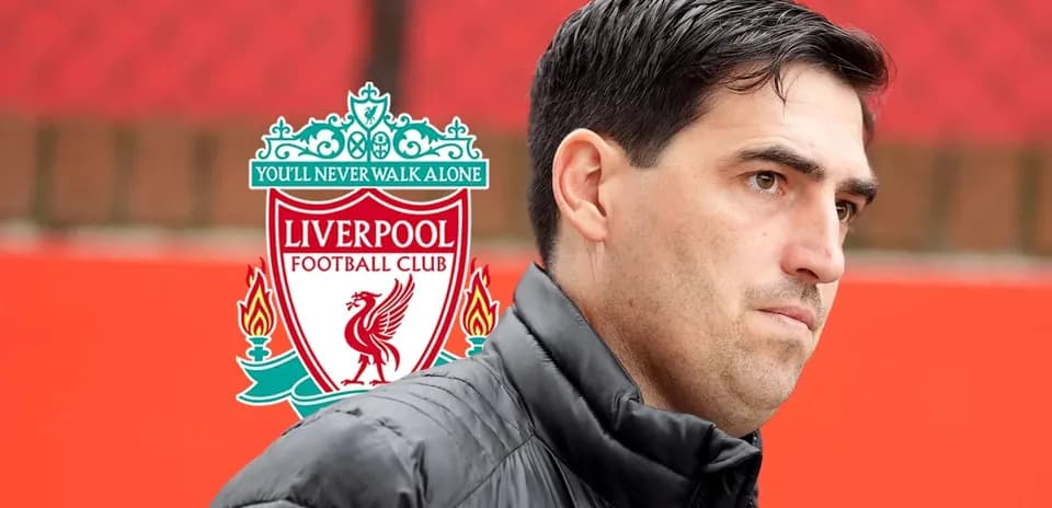 Coach standing near Liverpool FC logo backdrop