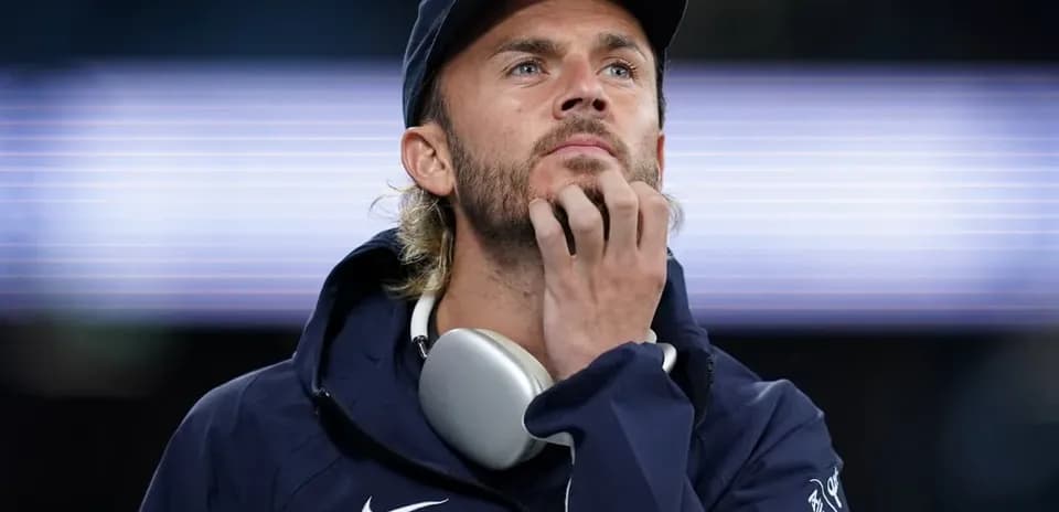 Man in sportswear thinking with headphones around neck