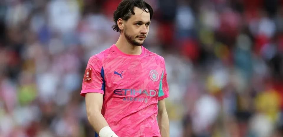 Goalkeeper in pink kit walking on pitch