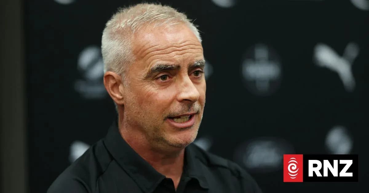 Coach speaking at press conference with logo backdrop