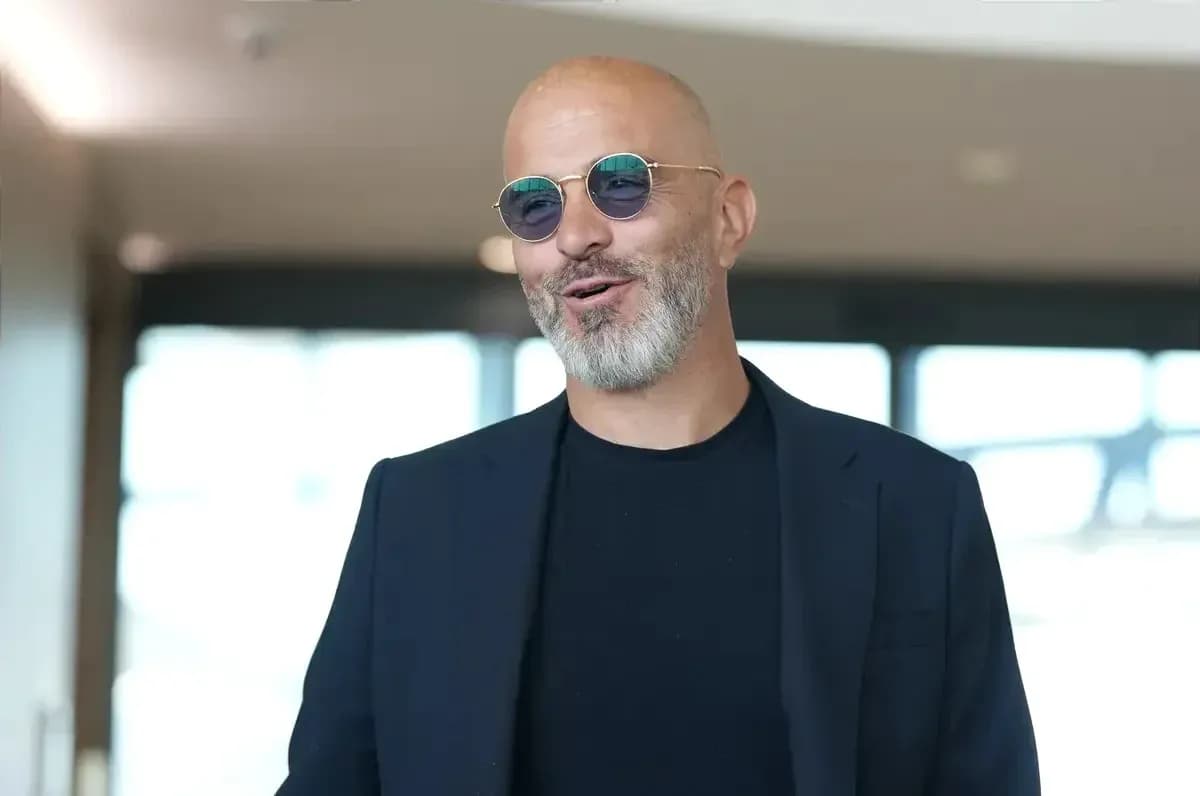 Man in sunglasses smiling indoors with blurred background