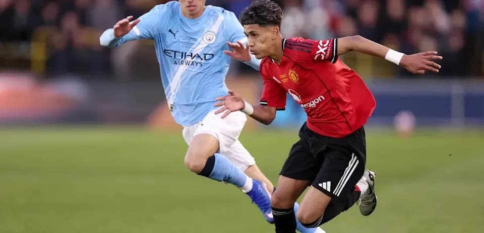 Manchester United player dribbling past Manchester City opponent