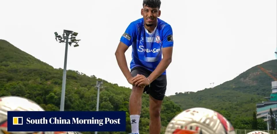Player posing on training ground with footballs