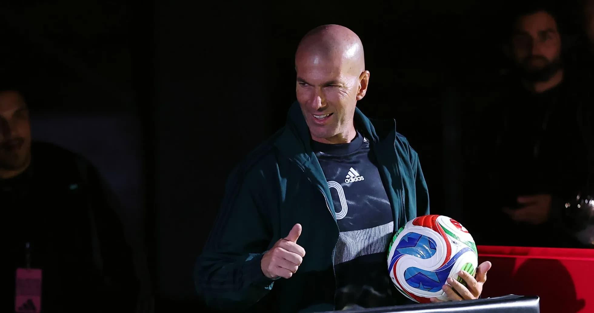 Zinedine Zidane holding a soccer ball with thumbs up