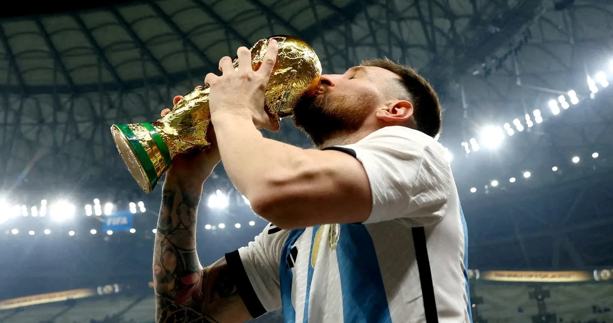 Player kissing FIFA World Cup trophy in stadium